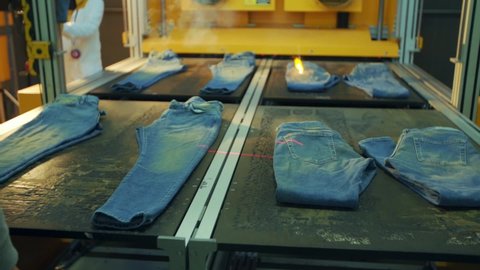 denim factory using laser beams to make design on blue jeans. Shooting of the latest technology laser machine in jeans making factory.