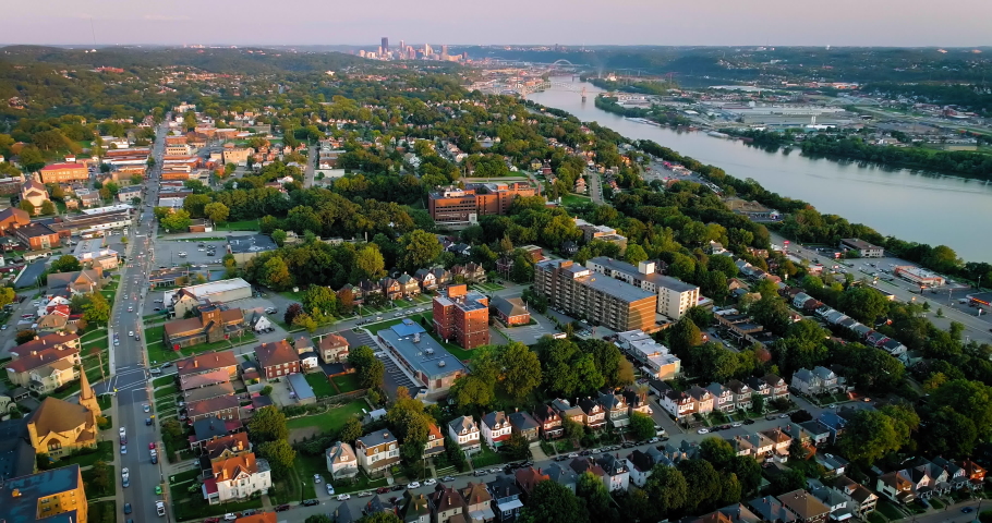 Drone flyover of a neighborhood with a river and city in the background filmed in Pittsburgh, PA. Royalty-Free Stock Footage #1058998217
