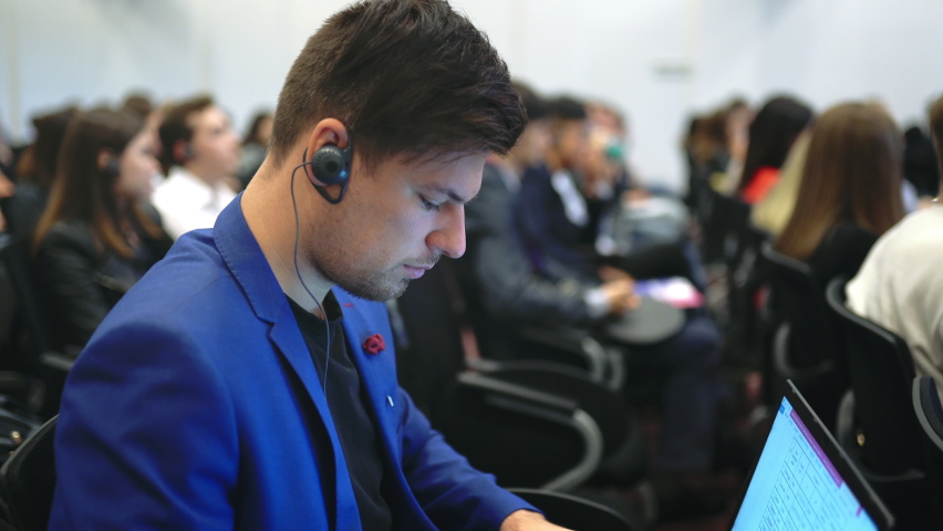 Person type keyboard crowded audience business forum. Viewer seminar listen speaker auditorium. Business man typing notebook political summit. Group people learning education speech in crowd audience.