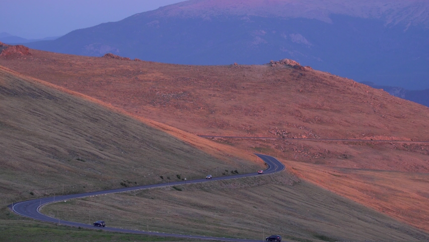 Cars driving in the Rocky Mountain National Park at sunset