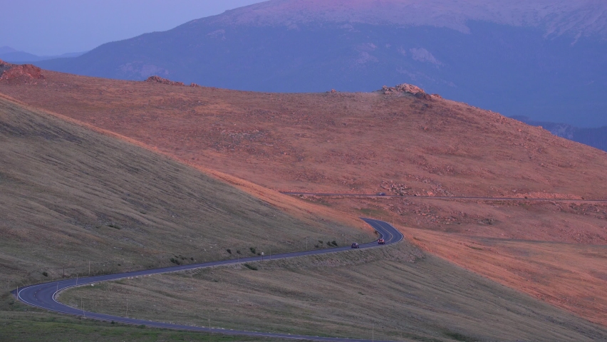 Cars driving in the Rocky Mountain National Park at sunset