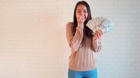 Excited Asian woman celebrating winning lots of money online in the lottery.