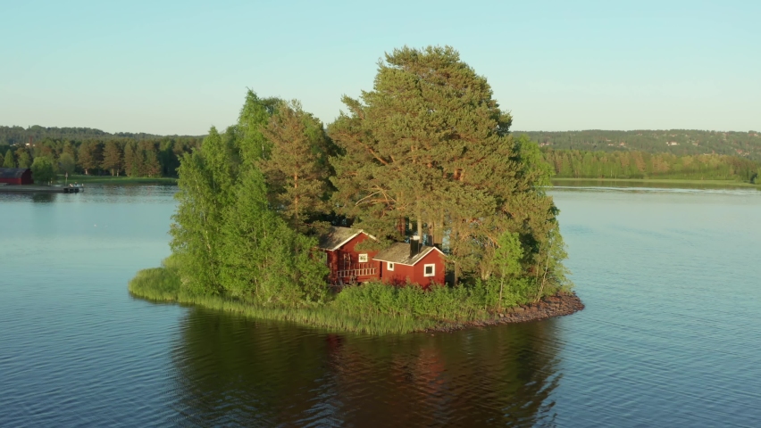 Red cabin on island. Sweden summer house in lake tiny remote between trees. Wooden Swedish home with beach. Stockholm archipelago cottage in aerial drone shot on beautiful summer evening  Royalty-Free Stock Footage #1059008051