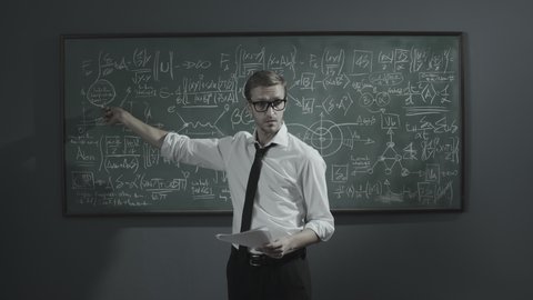 Young math professor holding a seminar, he is explaining math formulas and pointing, academic research and university concept
