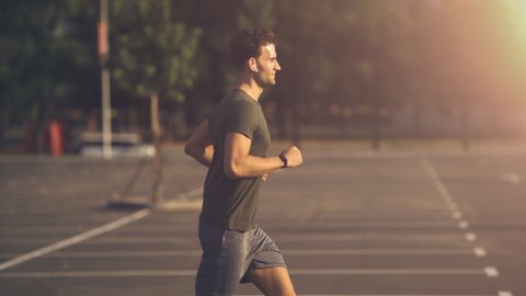 The smiling young man jogging in the morning. slow motion