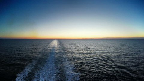 Water trace behind the large cruise ship on the Mediterranean sea in sunset, 4K UHD