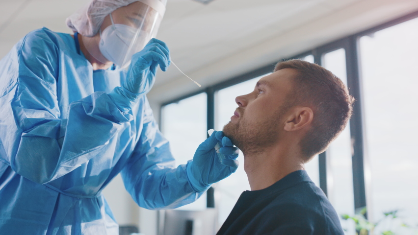 Medical Nurse in Safety Gloves and Mask, Protective Face Shield and Overalls is Taking a PCR Corona Virus Sample in a Health Clinic. Doctor Uses Respiratory Swab Test. Covid-19 Pandemic Concept. | Shutterstock HD Video #1059016355