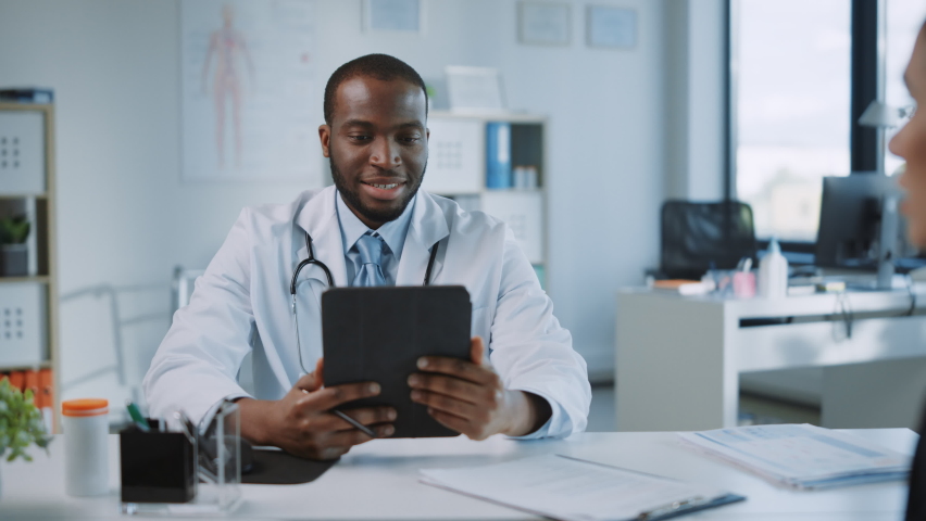 African American Medical Doctor Showing Mammography Test Results to a Patient on a Tablet Computer in a Health Clinic. Friendly Assistant Explains Importance of Breast Cancer Prevention Screening. Royalty-Free Stock Footage #1059016583