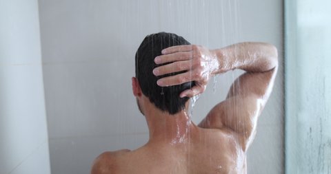 Man taking a shower enjoying showering under water falling from washing hairluxury rain shower head. Morning routine luxury bathroom. Male model showering. body care hygiene concept.