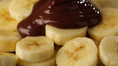 melted chocolate flows on sliced banana, close up