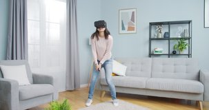 Asian woman playing video games in virtual reality in living room. Excited young female using vr glasses to enjoy tennis, squash at home. Entertainment, sports, training, app, technology.