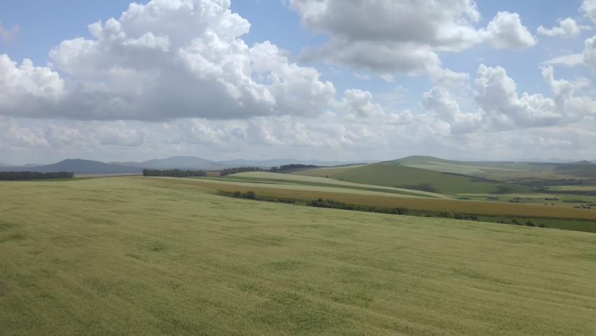 Scenic aerial panoramic view of idyllic rolling hills spring landscape in with lush green mountain pastures in evening light at sunset