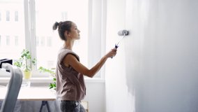 Young woman painting wall in apartment - Powered by Shutterstock - Get 15% off with code: PIKWIZARD15