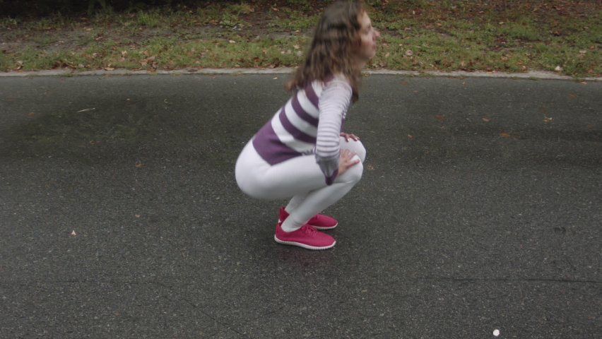 Woman exercising on a wet road after rain in the forest. Woman doing sports exercises for the legs.