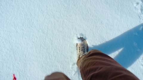 Hiking shoes POV walk on snow on winter hike, explorer boots leave footprints on fresh snow. Walking or hiking during winter season in mountains or forest. Winter outdoor activities