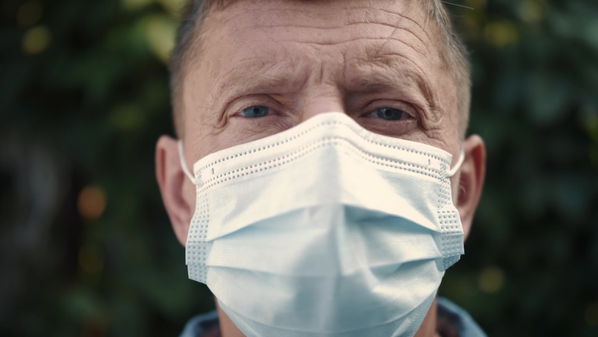 Close up portrait of charming mature man in medical face mask. Face of successful middle aged person. Confident professional older gentleman takes off protective medical mask looking at the camera. Royalty-Free Stock Footage #1059040511