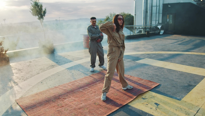 Dance battle. Competition. Skilled handsome urban guy breakdancing and performing hip hop stunts doing crazy movements. Cool girl waiting in background. Activities. Artists.