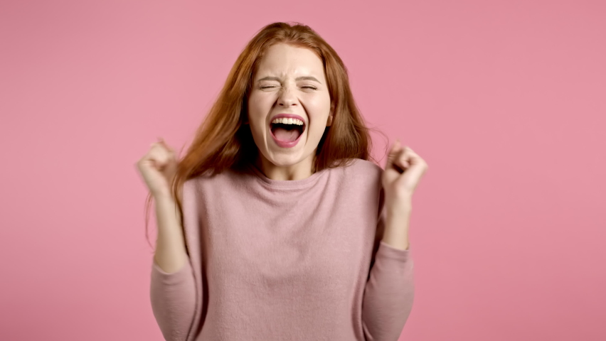 woman with red hair very glad, she screaming loud. Woman trying to get attention. Concept of sales, profitable offer. Excited happy lady on pink studio background. Royalty-Free Stock Footage #1059048707
