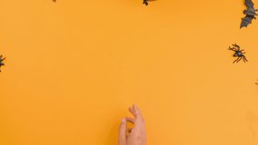 Happy halloween! A black balloon flies out of the hands on an orange background. Free space for text. Stop motion. High quality FullHD footage