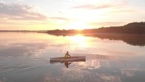 AERIAL Mid 50s Caucasian male canoeing on a traditional wooden boat on a large lake early in the morning. 4K UHD sunset shot - Powered by Shutterstock - Get 15% off with code: PIKWIZARD15