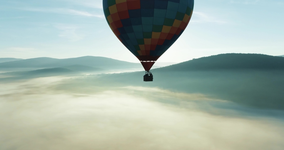 Colorful hot air balloon epic flying above mountain over the fog at sunrise with beautiful sky background - High altitude aerial drone wide view Royalty-Free Stock Footage #1059059570