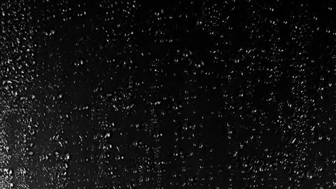 Close up view of Drops of rain trickling down on black background. Perfect Stock Footage for Digital Composing. Water Drops  on black glass background.