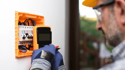Electrician at work with the tester measures the voltage in the electrical panel of a residential installation. Construction industry. Footage.