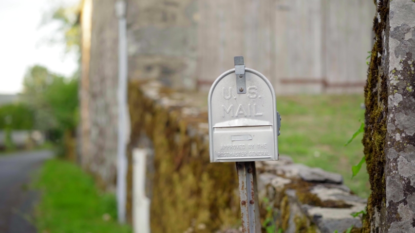 Man checking the mail in an empty US mail box, in a countryside green village