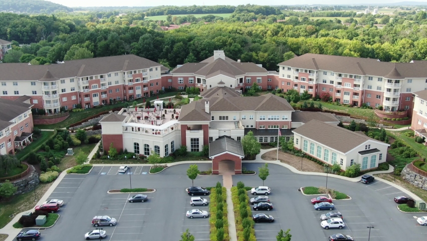 Descending aerial on retirement home community, assisted living, senior citizen home, large CCRC complex for continuing care, United States of America, USA Baby Boomer generation, healthcare facility | Shutterstock HD Video #1059068558