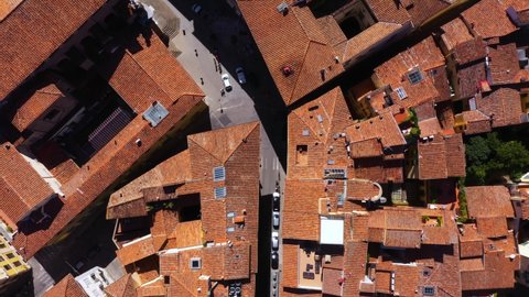 Top down view flying above roofs, roads and city on a sunny day in Florence in Italy in 4k.