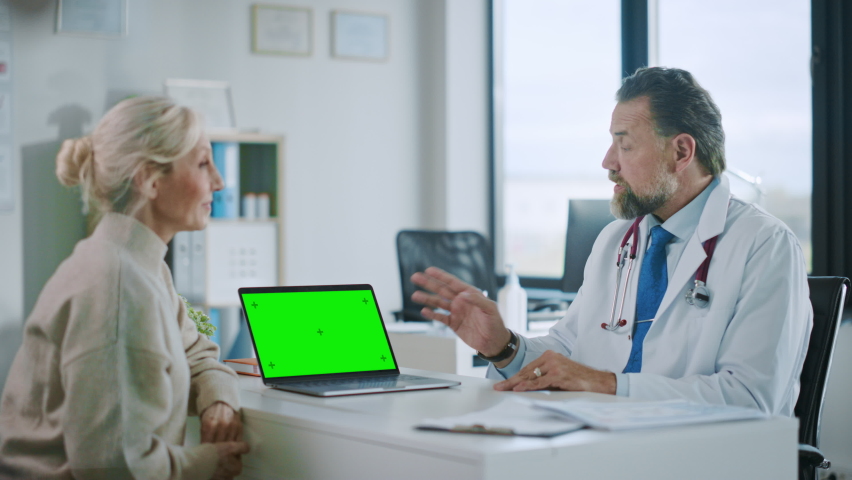 Family Medical Doctor is Explaining Diagnosis to a Senior Patient on a Computer with Green Screen in a Health Clinic. Assistant in White Lab Coat is Reading Medical History in Hospital Office. | Shutterstock HD Video #1059073877