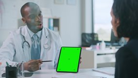African American Medical Doctor is Explaining Diagnosis to a Patient on a Tablet with Green Screen in a Health Clinic. Assistant in White Lab Coat is Reading Medical History in Hospital Office. - Powered by Shutterstock - Get 15% off with code: PIKWIZARD15