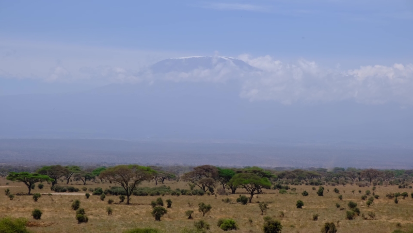 Mount Kilimanjaro in Tanzania rises above the clouds with savannah and grassland below.