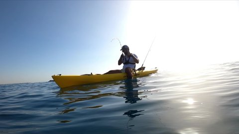 Mil Palmeras beach,Alicante, Spain, September 14, 2020: Kayak fishing underwater view of a little Fish hooked to a lure being pulled outof water by a fisherman standing on a kayak off the coast of Mil