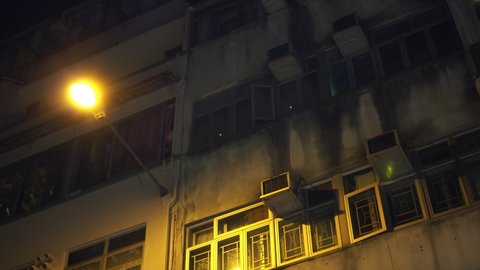 Old Hong Kong apartment building exterior at night with street lamp
