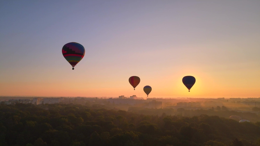 Aerial drone view of colorful hot air balloon flying over green park and river in small european city at summer sunrise, Kiev region, Ukraine Royalty-Free Stock Footage #1059090302