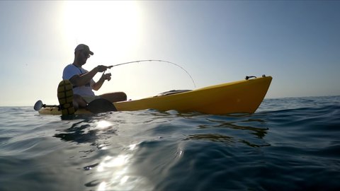 Mil Palmeras beach,Alicante, Spain, August 24, 2020: Kayak fishing, trolling fishing. A sportsman fishing in kayak underwater view of fish hooked to a lure being pulled out of water.