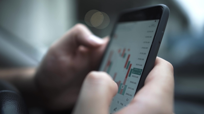 Hands with a mobile phone, checking stock market data. Scrolling through, touching stock market graph on a touch screen device close up handheld shot Royalty-Free Stock Footage #1059092354