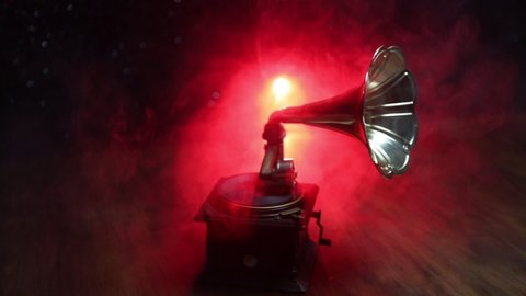 Music concept. Old gramophone on a dark background. Retro gramophone with disc on wooden table with toned backlight. Slider shot