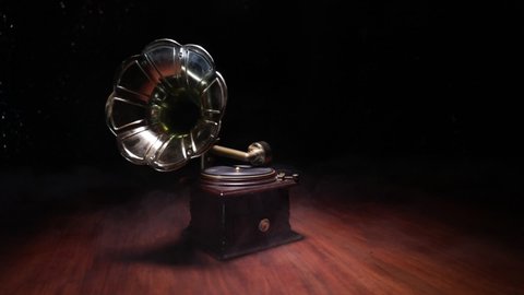 Music concept. Old gramophone on a dark background. Retro gramophone with disc on wooden table with toned backlight. Slider shot