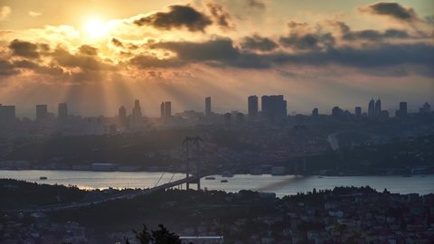 Sunset time lapse clip on a cloudy day with Bosphorus Bridge (15 Temmuz Bridge), skyscrappers and buildings. Panorama clip taken in Istanbul, Turkey.