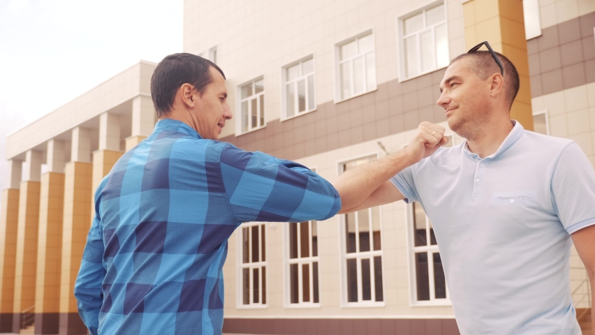 Two businessmen touch elbows social distance. bump avoid greeting. coronavirus pandemic concept. two men meeting greet each other at distance observing social distance lifestyle. bump avoid greeting | Shutterstock HD Video #1059098138