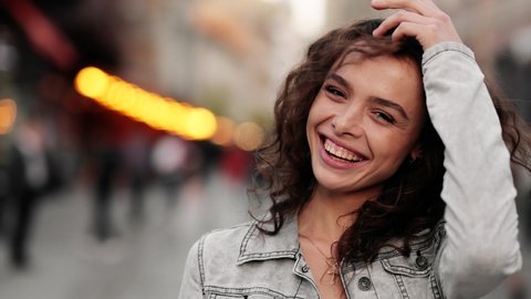Close-up portrait of smiling girl looking at. Curly hair fashion model face smiling. Portrait of joyful girl open eyes. Female nature beauty