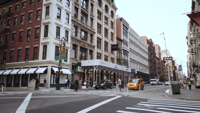 New York / USA - Sep 14, 2020: Empty NYC streets in Soho. Filmed during Coronavirus Pandemic reopening phase 4. View of Broadway which usually is crowded. Young people and taxi crossing intersection.