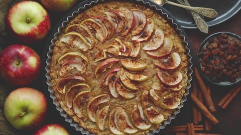 Homemade Apple tart pie with fresh fruits and cinnamon sticks on rusty background. Top view, flat lay. Video stock
