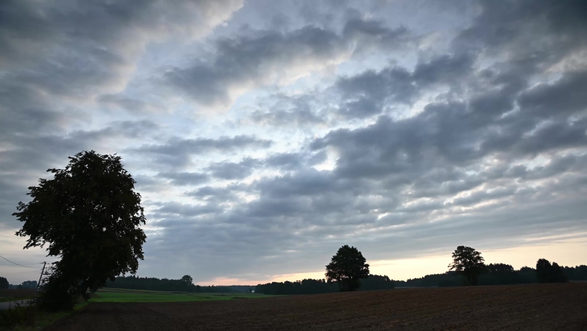 Plowed field at sunrise with flowing clouds