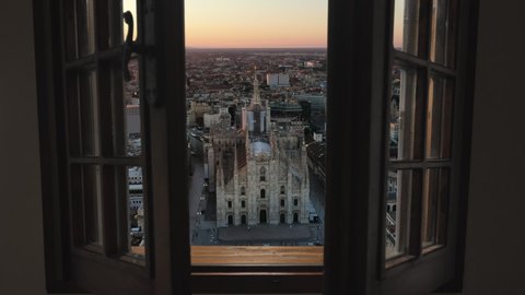 Milan cathedral piazza del duomo aerial view, drone moving out from inside house through the window at sunrise