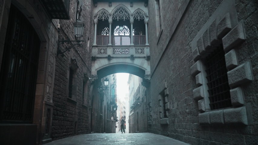 Beautiful brunette making photo under the arch. Young attractive woman taking pictures of stunning gothic buildings. Pretty tourist makes selfie in a beautiful city. Girl with mobile phone.