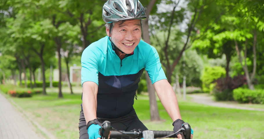 Close up of asian old man wearing helmet is cycling a bicycle in the park - enjoying sport or hobby living healthy Royalty-Free Stock Footage #1059110396