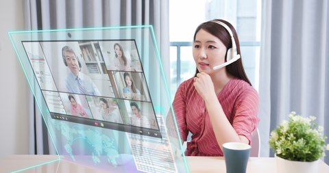 In the near future asian businesswoman join online video meeting while working on transparent display computer at home